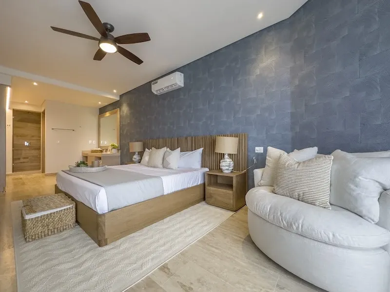 Recámara principal de Sole BLU con cama king, ventilador de techo y muro texturizado azul