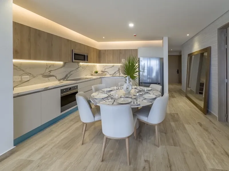Cocina de Sole BLU con frente de mármol, alacena de madera y comedor para seis